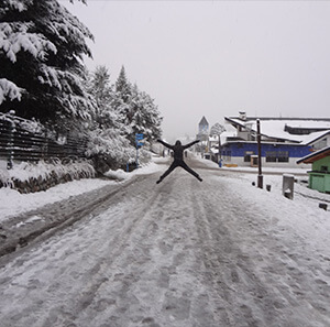 Pepe de braços abertos pulando sobre estrada cheia de neve.