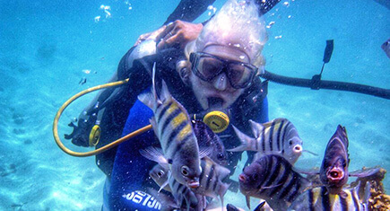 Lucas mergulhando em Maragogi (Alagoas). Mar azul cercado por peixes.
