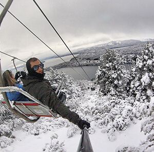 Selfie no teleférico para Cerro Otto. Paisagem linda com muita neve, árvores branquinhas e lago ao fundo.