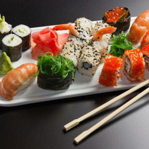 Foto de várias peças diferentes de sushi e dois hashis