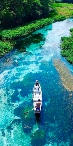 Foto aérea de um rio com um barco de pequeno porte.