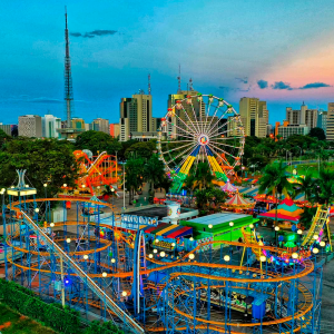Vista aérea de um parque de diversões com vários brinquedos do parque ao final da tarde.