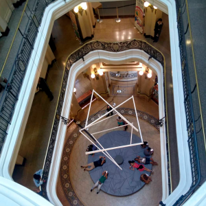 Foto aérea do entorno do Centro Cultural com uma escultura abstrata no meio e pessoas a observando no fundo.