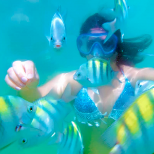 Foto de mulher com mascara de mergulho embaixo da água com peixes