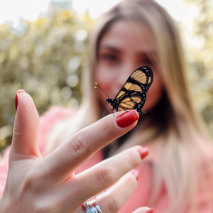 Foto de uma menina com uma borboleta pousada em seu dedo