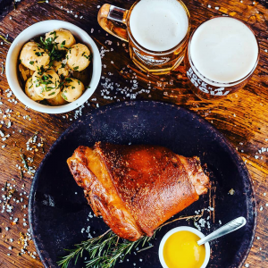 Foto de dois copos de chopp, batatas e um prato com carne do Crow Beer.