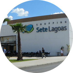Foto da fachada do Shopping Sete Lagoas. Fachada branca, com um coqueiro na frente.