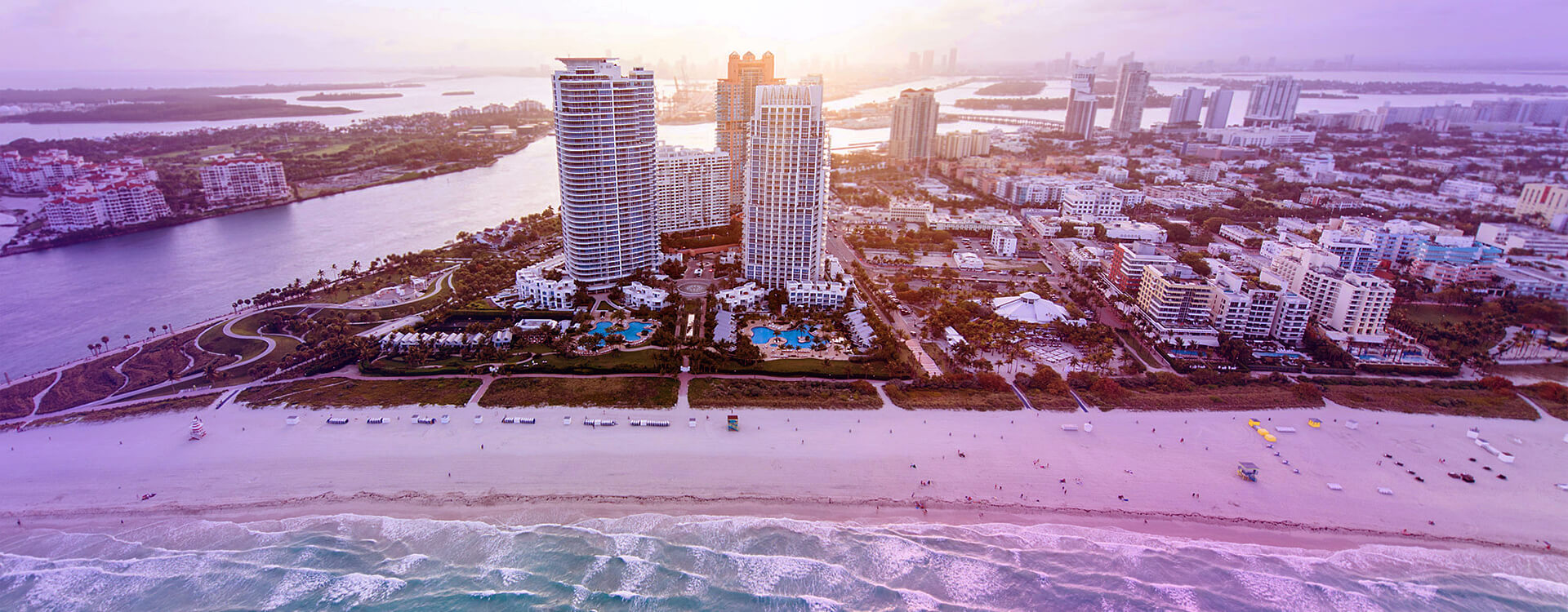 Vista aérea de Miami. Praia e prédios ao fundo.