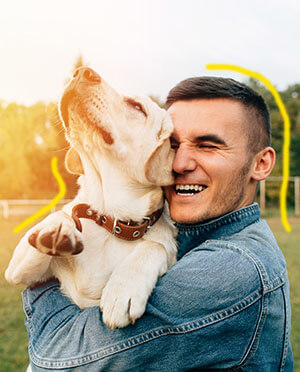 Um homem sorrindo abraçado em seu cachorro